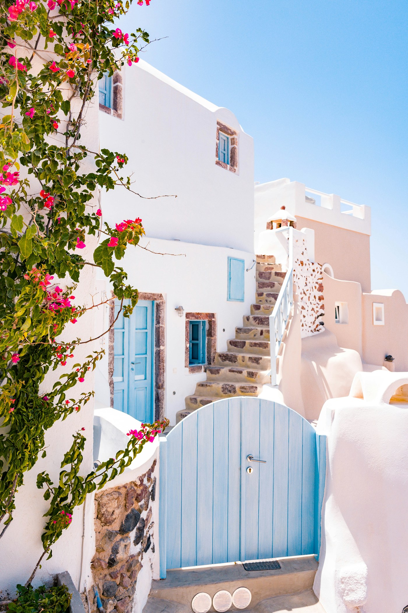 Whitewashed Mediterranean architecture with blue doors and bougainvillea